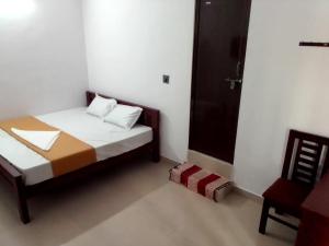 1 dormitorio pequeño con 1 cama y 1 silla en Emirates Residency, en Pudunagaram
