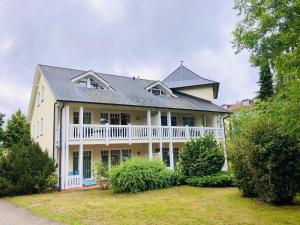 ein großes weißes Haus mit einem Walmdach in der Unterkunft Dünenpark Binz - Komfortplus Ferienwohnung mit 2 Schlafzimmern und Terrasse 187 in Binz