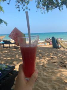 a person holding a drink in front of the beach at Sunray Beach House in Tangalle