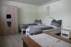 a bedroom with two beds and a table in it at Pension Hüttendorf 49 gradnord in Bayerisch Eisenstein