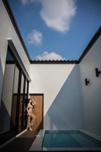 a woman standing next to a swimming pool in a house at VEVILLA in Bangkok