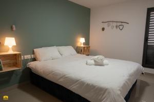 a bedroom with a large white bed with two lamps at צימר עלמא in Yeroẖam +16 photos