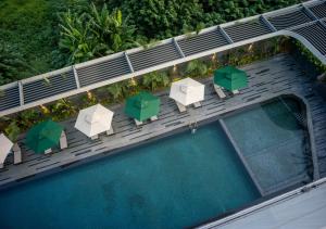 einen Blick über einen Pool mit Stühlen und Sonnenschirmen in der Unterkunft Fraser Residence Hanoi in Hanoi