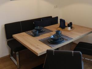 a table with black chairs and a wooden table with plates and cups at Ferienwohnung an der Jodquelle in Bad Endorf