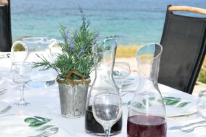 a table with wine glasses and a potted plant on it at Sun Senses - villa with private beach in Ayía Marína