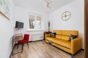 salon z żółtą kanapą i czerwonym krzesłem w obiekcie Apartments Osiedle Szkolne Cracow by Noclegi Renters w Krakowie