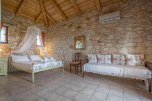 a bedroom with two beds and a stone wall at Myrties stone houses - Ta Petrina in Vasilikos