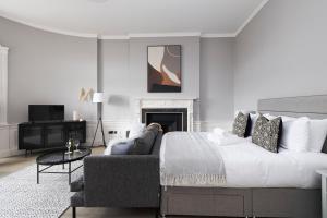 una camera da letto con un letto, un divano e una televisione di JOIVY Modern Studio in New Town, on Historic George Street a Edimburgo