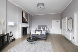 un soggiorno con divano e camino di JOIVY Modern Studio in New Town, on Historic George Street a Edimburgo