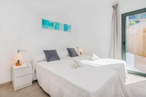 a white bedroom with a bed and a window at Mirador Blue G in Cala de Sant Vicenc