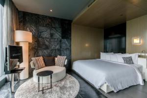 a hotel room with a bed and a chair at SO BANGKOK - SHA Extra Plus in Bangkok