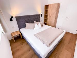 a bedroom with a large white bed with a gray headboard at Glüxplatzl Appartements am Wald in Sankt Martin am Tennengebirge