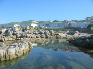a river with rocks in front of some houses at Beachfront Cottage - Hermanus Whale View in Hermanus