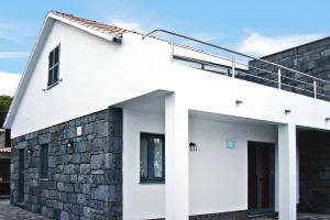 una casa blanca con una pared de ladrillo en Semi detached houses Pra nha de Baixo Pico Azores, en Prainha de Baixo