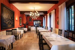 un restaurante con mesas y sillas blancas y una lámpara de araña en Hotel Locanda Stendhal, en Colorno