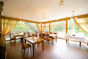 een eetkamer met tafels, stoelen en ramen bij Villa Hotel Theresa in Rakvere