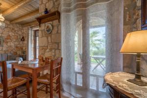 a dining room with a table and a large window at Myrties stone houses - Ta Petrina in Vasilikos