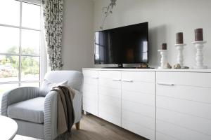 uma sala de estar com televisão numa cómoda branca em Holiday house, Fuhlendorf em Fuhlendorf