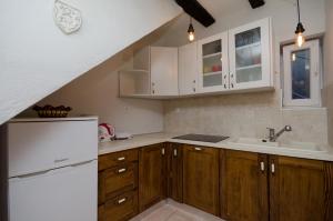 a kitchen with wooden cabinets and a white refrigerator at Under Ancient Roofs Vrbnik in Vrbnik