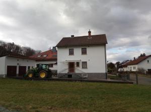 un trattore parcheggiato di fronte a una casa bianca di Ferienwohnung Zum Bienenstock a Mörlenbach