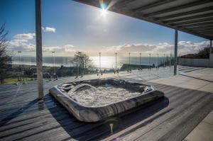 a hot tub on a deck with a view of the ocean at Sunrise - 5 Bedroom Luxurious Holiday Home - Pendine in Pendine