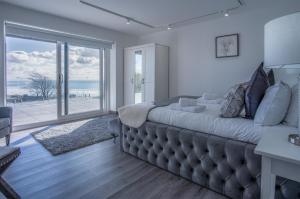 a bedroom with a large bed with a view of the ocean at Sunrise - 5 Bedroom Luxurious Holiday Home - Pendine in Pendine