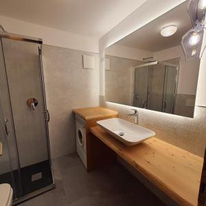 ein Bad mit einem Waschbecken und einem Spiegel in der Unterkunft Casa Maddalena in Canazei