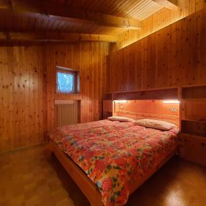 ein Schlafzimmer mit einem Bett in einem Holzzimmer in der Unterkunft Casa Maddalena in Canazei