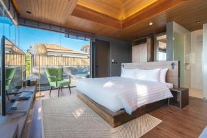 - une chambre avec un lit et un balcon avec une télévision dans l'établissement AKRA Collection Layan, à Layan Beach