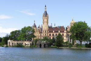 a large building with a tower on top of a lake at Ferienhaus mit Pool und Sauna am Duemmer See in Dümmer