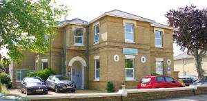 una casa di mattoni con macchine parcheggiate di fronte di Parterre Holiday Apartments a Sandown