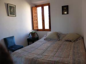 ein Schlafzimmer mit einem Bett, einem Stuhl und einem Fenster in der Unterkunft Albergue el Hacedor in La Aldea del Portillo de Busto