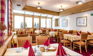 un restaurant avec des tables, des chaises et des serviettes rouges dans l'établissement Hotel Montana, à Ischgl