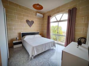 - une chambre avec un lit et une grande fenêtre dans l'établissement Wilga Summit Apartment A, à Qala