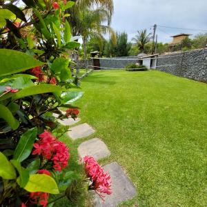 einen Garten mit roten Blumen und einem Steinweg in der Unterkunft Casa Buzios Geriba in Búzios