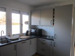 uma cozinha com armários brancos e um micro-ondas em Le Petit Chalet em Resteigne