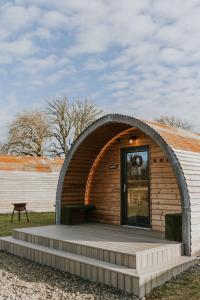 mały drewniany budynek z drzwiami na polu w obiekcie Doxford Farm Camping w mieście Alnwick