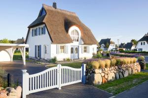 a white house with a thatched roof and a fence at Holiday house, Fuhlendorf in Fuhlendorf