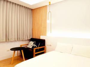 a bedroom with a bed and a chair next to a window at 站前夥伴旅宿 in Hualien City +32 photos