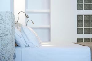 un letto con cuscini bianchi e una lampada; di Kanale's Rooms & Suites a Naoussa