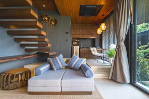 a living room with a couch and a staircase at AKRA Collection Layan in Layan Beach