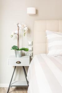 a white side table with a plant on it next to a bed at A17 Modern & Cosy 2R flat up to 4ppl near Parthenon in Athens
