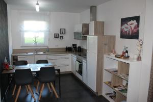 eine Küche mit weißen Schränken sowie einem Tisch und Stühlen in der Unterkunft Ferienwohnung Hesselberg in Balingen