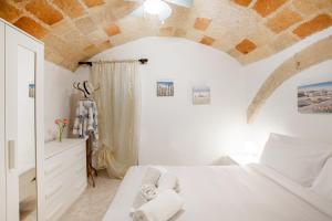 a bedroom with a white bed and a brick wall at Monopoli Heartbeat - Apartment 200m from Sea in Monopoli