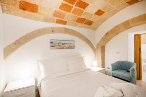 a bedroom with a white bed and a blue chair at Monopoli Heartbeat - Apartment 200m from Sea in Monopoli