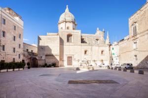 a large building with a clock tower in a courtyard at Monopoli Heartbeat - Apartment 200m from Sea in Monopoli