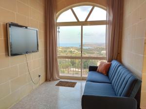 - un salon avec un canapé bleu et une grande fenêtre dans l'établissement Wilga Summit Apartment A, à Qala