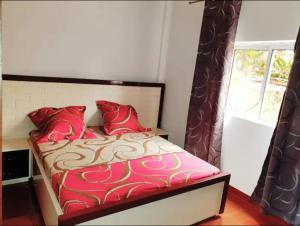 a bedroom with a bed with red pillows and a window at Your home in Yaoundé