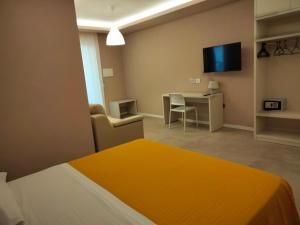 a room with a bed and a desk and a television at Loris House in Tropea