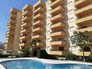 an apartment building with a swimming pool in front of it at Tamaris Playa Solo Familias Serviplaya in Playa de Xeraco